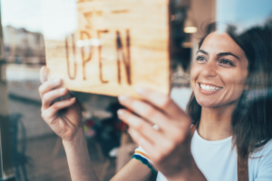 Image of woman putting open open sign for her business.